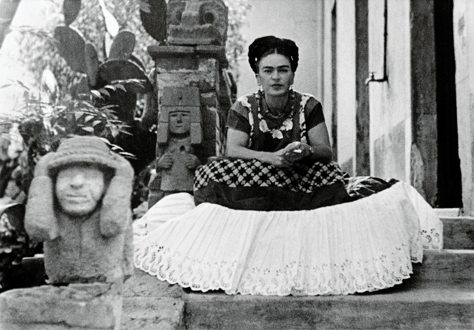 Photo of Frida sitting next to sculpture by Mardonio Magana